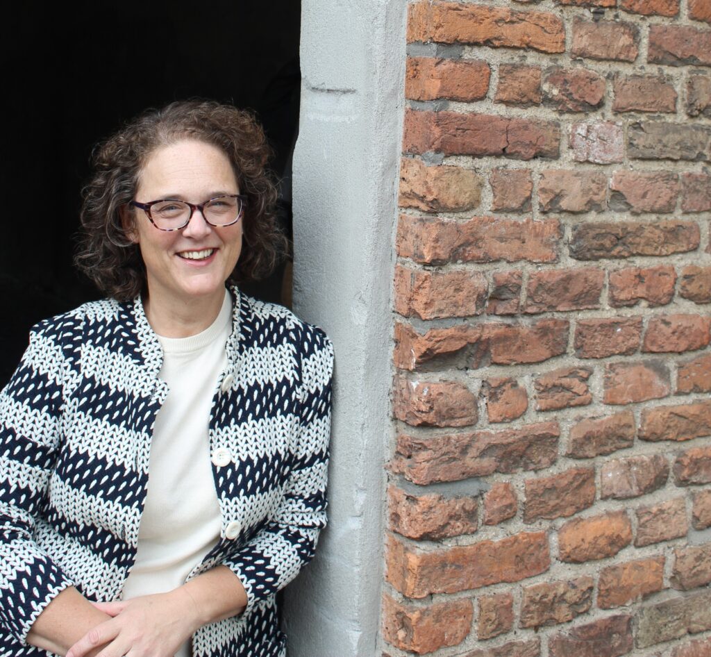Miranda leunt tegen een muur in Deventer en kijkt lachend de camera in.