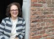 Miranda leunt tegen een muur in Deventer en kijkt lachend de camera in.
