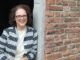 Miranda leunt tegen een muur in Deventer en kijkt lachend de camera in.